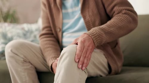 Senior, hombre y sofá con manos para el dolor de rodilla o el envejecimiento de las articulaciones, la inflamación