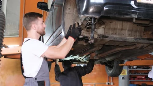 A Professional Car Mechanic Examines a Car at a Car Service Performing a Series of Tests