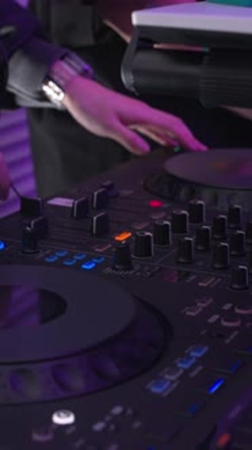 Close-up of a DJ's hands mixing music on a turntable at a party.