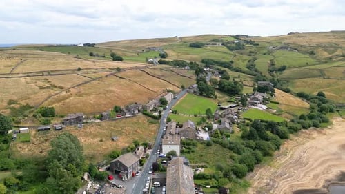 Aerial footage of a rural industrial Yorkshire town village with old mill and chimney stack. Shot at