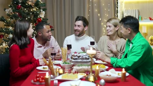 Friends celebrate Christmas eve or New Year holiday paty together sitting at the table. Feast