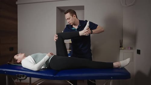 A Male Osteopath Performs Physical Therapy on a Female Patient The Doctor Looks at the Condition of