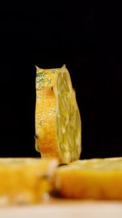 Vertical video. A slice of Kiwano cucumber rotates on a black background amidst the pieces