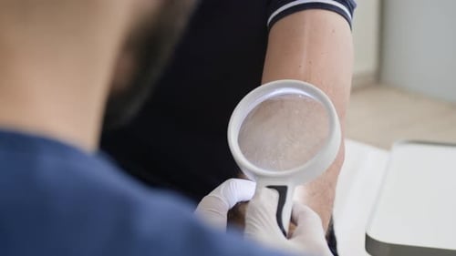 Dermatologist Examining Elbow through Magnifying Glass for Skin Problems
