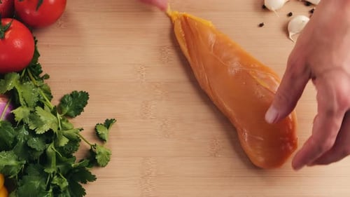 Man Slicing Raw Turkey or Chicken Meat Fillet on Oak Cutting Board Closeup Cooking with Knife on