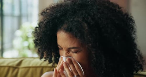 Mujer, estornuda y pañuelos en el sofá de su casa, enferma y sinusitis con gripe, alergia