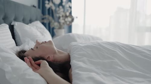 Woman Relaxing Peacefully in Bed with Natural Morning Light
