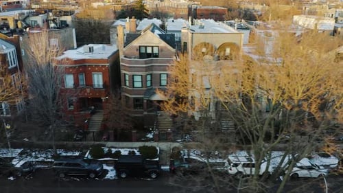 Aerial, suburban street lined townhouses, cars and winter snow, slide left