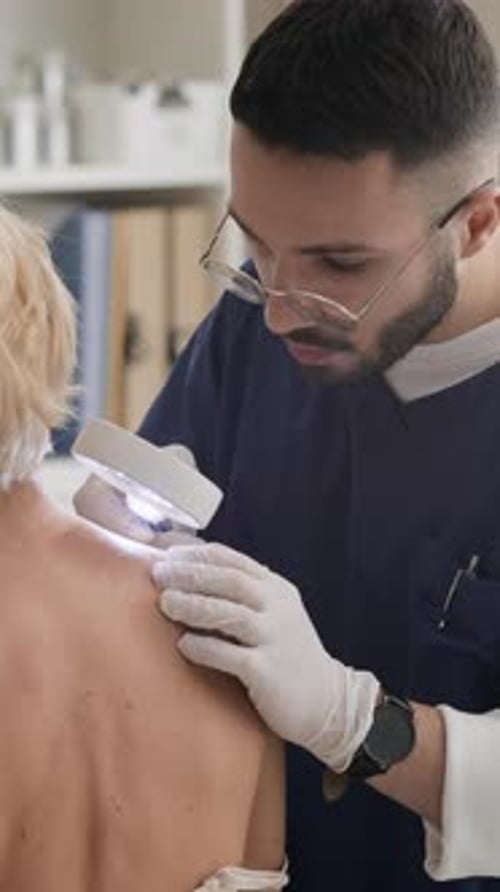 Middle Eastern Male Dermatologist Examining Skin with Magnifying Glass