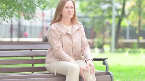 Mulher idosa sênior sentada ao ar livre com dor no joelho