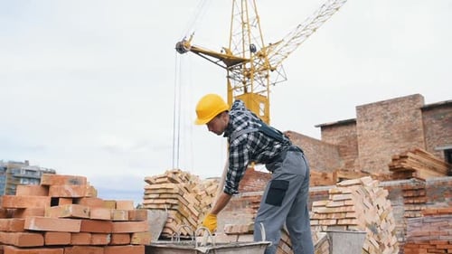 Uses shovel. Construction worker in uniform and safety equipment have job on building