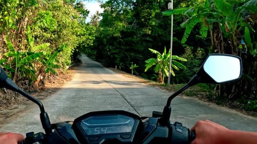 Exploring a scenic countryside road on a motorcycle in the afternoon sun