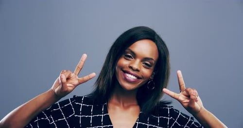 4k video footage a young woman showing the peace sign against a grey background