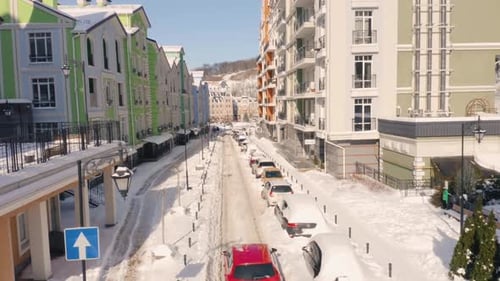 Aerial Back View of Red Car Driving Along Street Covered with Snow