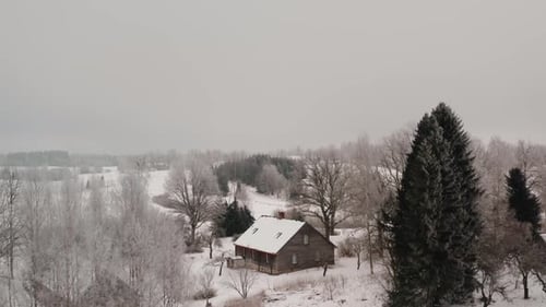 Ascending drone shot of a family home in the countryside on a white winter day with lots of snow and