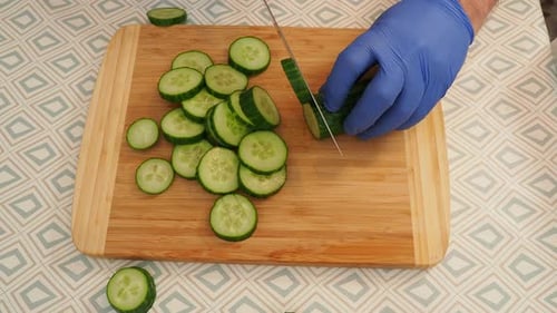 Cucumbers and tomatoes are cut on a cutting board for salad.