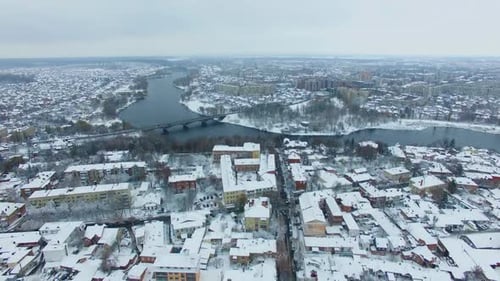City panorama with river and bridge over it. Snowy winter daytime drone footage.