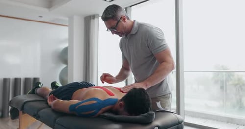Rehabilitation, physiotherapy and man with tape on back for wellness, reflexology and biokinetics