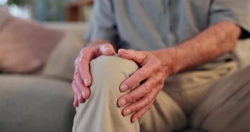 Hombre mayor, dolor de manos y rodillas en el sofá de su casa con artritis y dolor muscular como enfermedad crónica