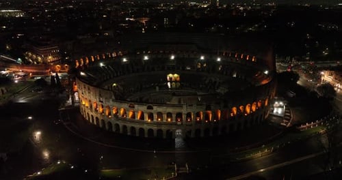 Aerial fly drone view of Colosseum or Coliseum at night, Rome, Italy, Europe. Ancient Roman ruin is