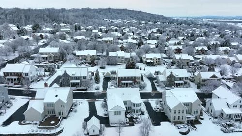 Neighborhood aerial during snowstorm. Snowflakes cover USA suburban homes and houses in modern housi