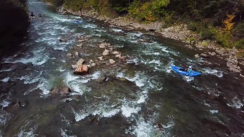 Four Sportsmans in Blue Inflatable Canoes are Rafting Down a Mountain River