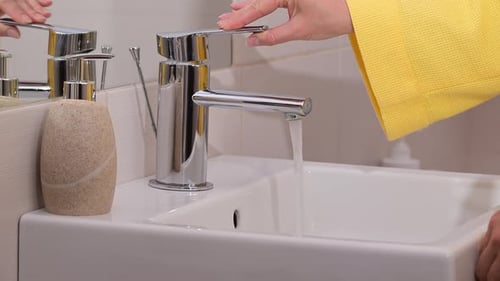 Woman open the faucet and washing hands.
