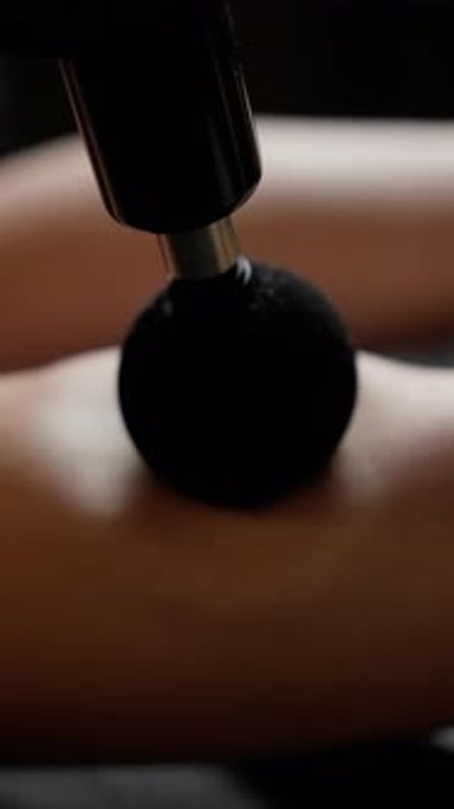 Masseur Providing a Soothing Massage to a Client Using a Percussion Massager on Their Arm Promoting