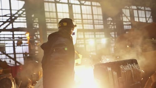 A Worker Skillfully Handles Molten Metal in a Busy Industrial Setting Focusing on Safety Stock Clip