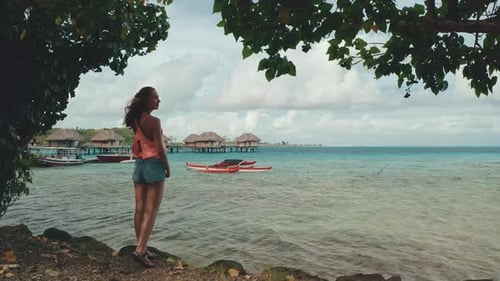 Woman Stand on Coast Look at Sea with Wooden Huts