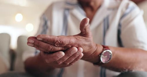 Manos, dolor y artritis con masaje para una persona en el sofá con muñeca lesionada