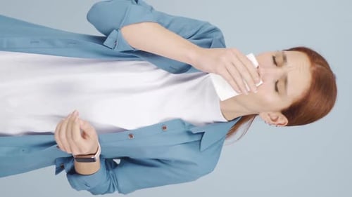 Vídeo vertical de una mujer cubriéndose la boca y la nariz mientras tose.