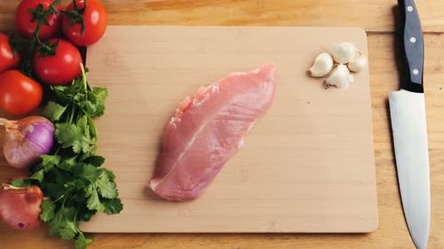 Man Slicing Raw Turkey or Chicken Meat Fillet on Oak Cutting Board Closeup Cooking with Knife on