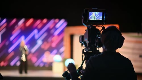 Cameraman filming a music performance on a professional TV camera. Backstage shooting television sho