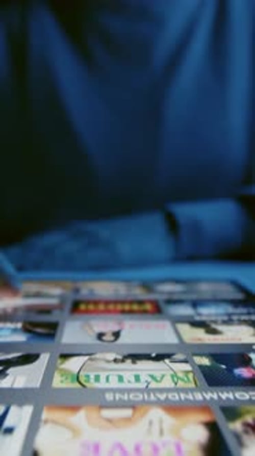 Hand of Woman Scrolling through Movies on Streaming App on Tablet