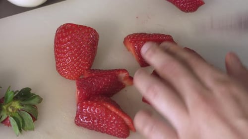 Red Strawberries Cut In Half And Quarter Using A Knife On The Chopping Board. - close up shot