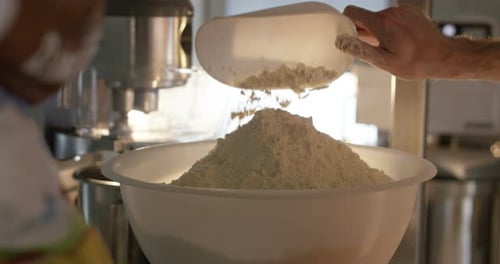 An experienced chef in a professional kitchen prepares the dough with flour to make the bio Italia