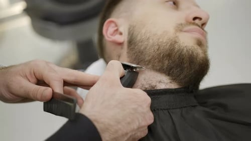A Professional Barber Skillfully Trimming a Mans Beard with Remarkable Precision and Care Clip