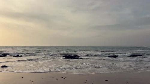 View of the shore with rocks of a calm sea under a cloudy sky.