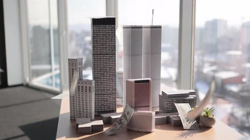 Paper Dollars Hundred Banknotes Falling on Architectural Scale Cardboard Model of Building Complex