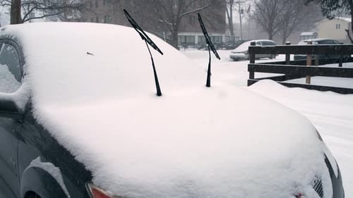 Snow-covered car in a snowstorm with windshield wipers up