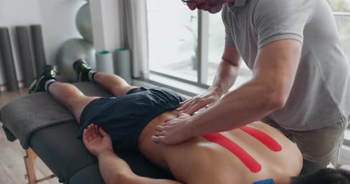 Rehabilitation, physiotherapy and man with tape for back pain for wellness