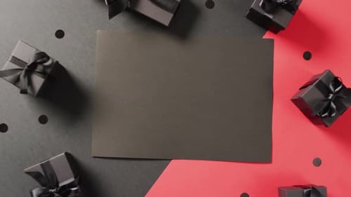 Black gift boxes with black ribbons on black and red background with copy space