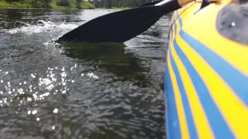 Close up view of a raft seen paddling through a river. The raft is yellow with blue stripes.