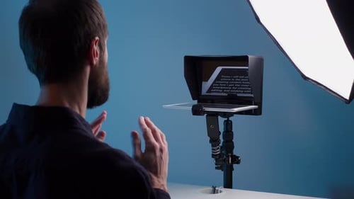 A Young Male Bloger Records a Video with Teleprompter for His YouTube Channel in His Studio
