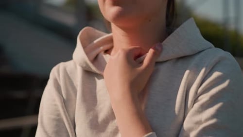 CloseUp of Woman Holding Hoodie Outdoors in Empty Stadium with Blurred Background