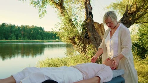 Terapeuta realizando massagem de pontos espirituais debaixo de uma árvore para relaxamento e canalização profissional