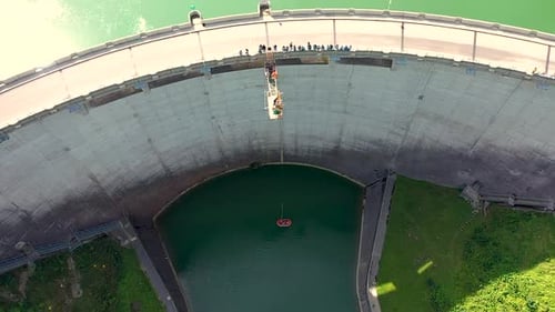 Birds eye top down Aerial view of young people bungee jumping off a 50m high dam platform while view