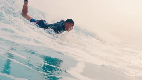 Surfing in Maldives. Man paddles and takes off on the ocean wave in tropics