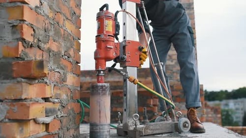 Uses electrical device. Construction worker in uniform and safety equipment have job on building